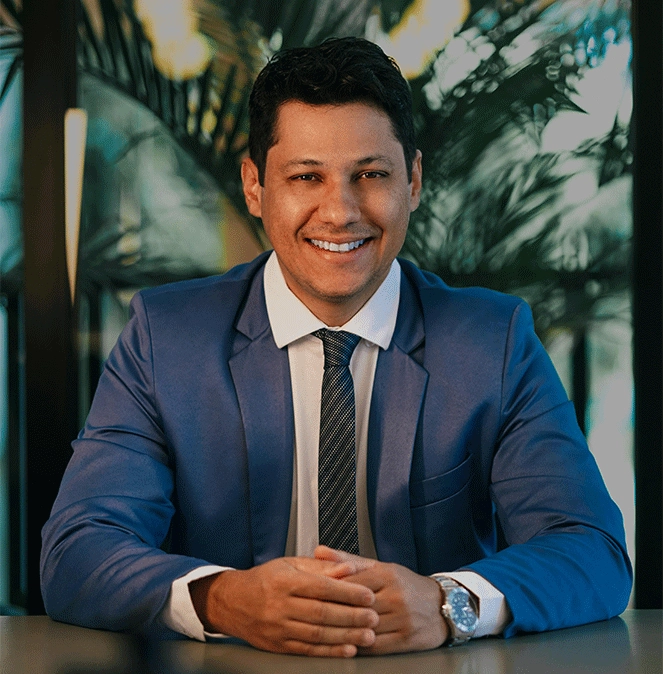 hispanic man at table wearing suit and tie smiling